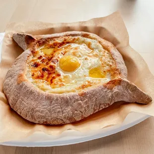 Adjaruli khachapuri (bread boat) - Fluffy bread boat with cheese, grass-fed butter, and egg yolk.