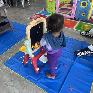 Toddler at play. Baby easel to accommodate the infant and toddlers.