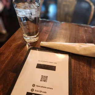 a glass of water and a menu on a table