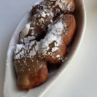 a plate of powdered sugared donuts
