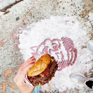 a person holding a hamburger in their hand