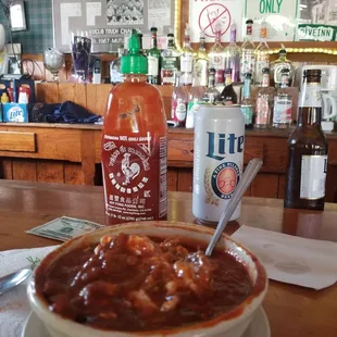 a bowl of chili and a bottle of hot sauce