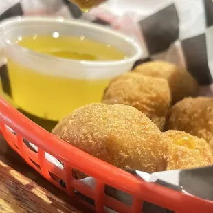 a basket of fried doughnuts and dipping sauce
