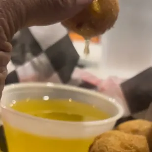 a person dipping a donut into a bowl of mustard