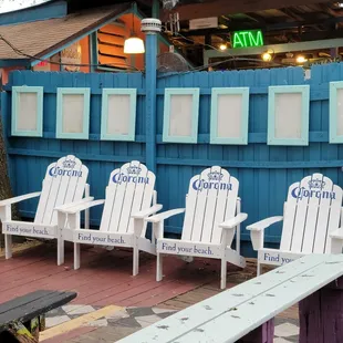 a row of white chairs in front of a blue fence