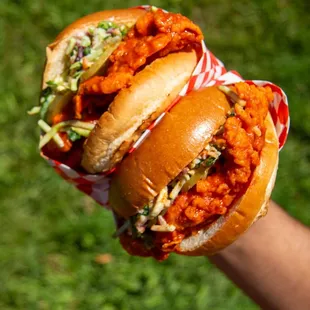 a hand holding two sandwiches