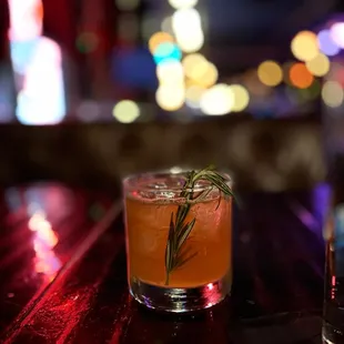 a cocktail with a sprig of rosemary