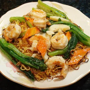 a plate of noodles with shrimp and vegetables