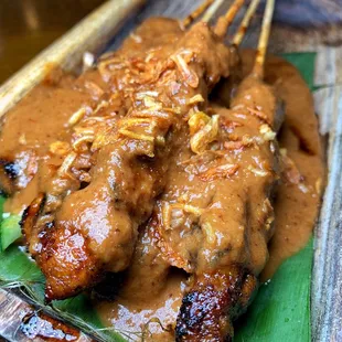 a plate of meat skewered on a banana leaf