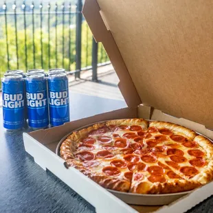 a pizza in a box and a can of bud bud