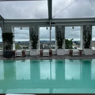 a pool and lounge chairs with a view of the city