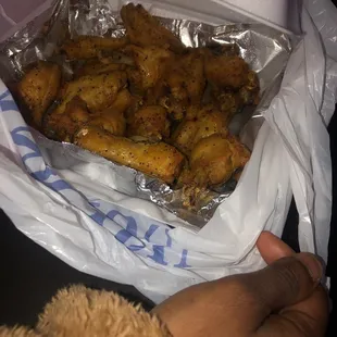 a person holding a bag of fried chicken