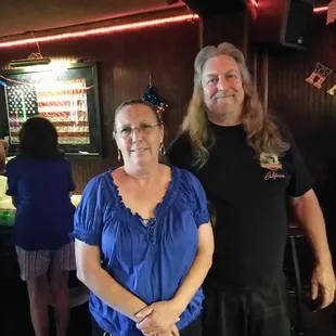 a man and a woman standing in front of a bar