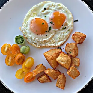 Sunny side up eggs with potatoes and tomatoes.