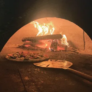 a pizza being cooked in a brick oven