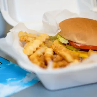 a burger and fries in a styrofoam container