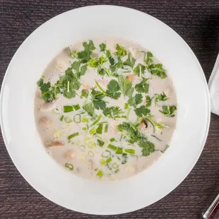 Tom Kha soup.                             Sour coconut soup with kaffir lime leaves,ginger,button mushrooms,tomatoes,and choice of protein
