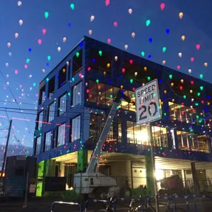 Current view of construction through the window with the reflection of their ceiling&apos;s Christmas lights.