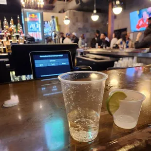 a shot of a drink and a laptop on a bar