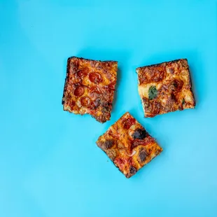 three pieces of pizza on a blue surface