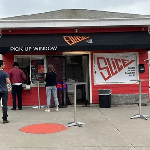 people standing outside of a pick up window