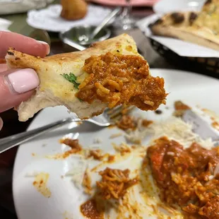 a hand holding a piece of pizza