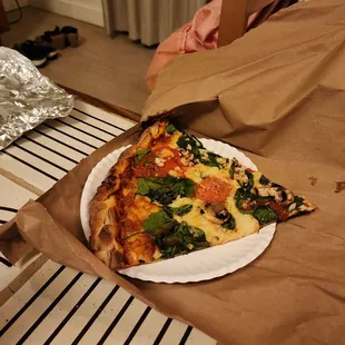 a slice of pizza on a paper plate