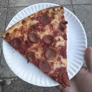 a slice of pepperoni pizza on a paper plate