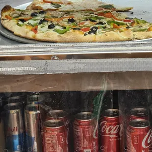 a slice of pizza and cans of soda
