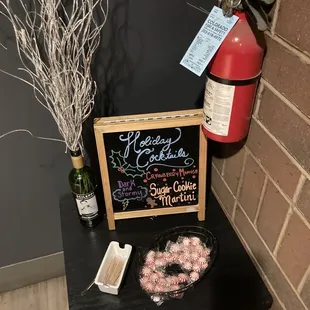 a table with a sign and a bowl of doughnuts