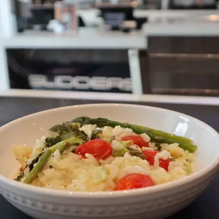a bowl of rice with asparagus and tomatoes