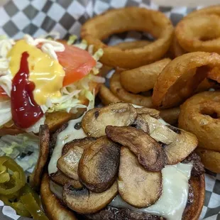 Dressed mushroom and Swiss burger with onion rings.