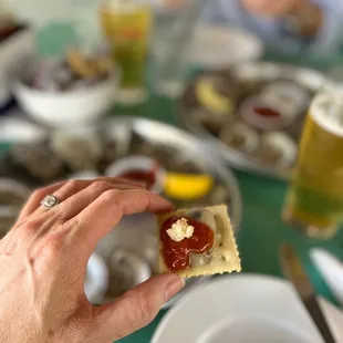 a hand holding a cracker with ketchup