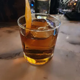 a glass of whiskey with an orange slice