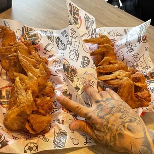 a hand grabbing a piece of fried chicken