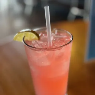 a pink drink with a lemon wedge