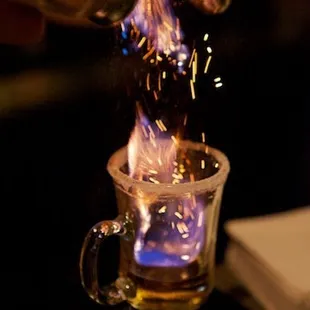 a person pouring liquid into a shot glass
