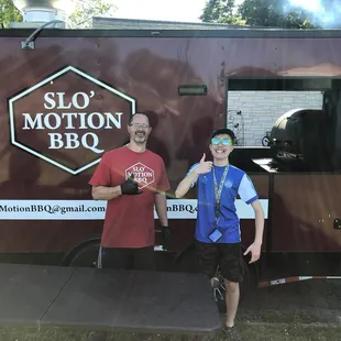 two men standing in front of a food truck