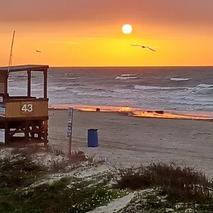 a lifeguard stand on the beach at sunset