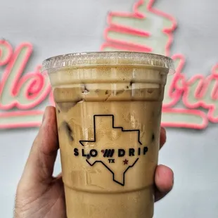 a hand holding a cup of iced coffee