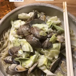 a bowl of noodles and clams with chopsticks