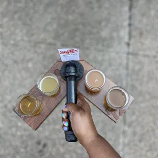 a person holding a microphone and several glasses of beer