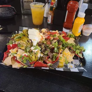 a plate of nachos and a glass of orange juice