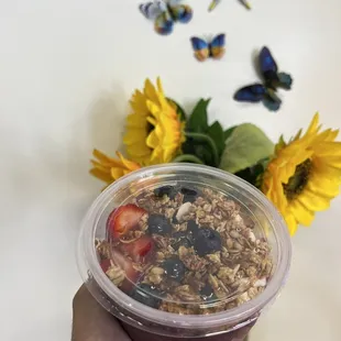 a hand holding a cup of tea and a vase of sunflowers
