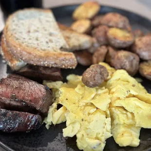 Steak and eggs scrambled with house potatoes and toast