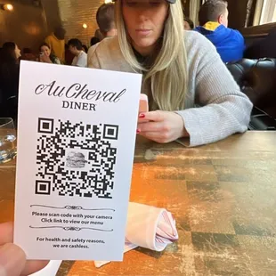 a woman sitting at a table with a qr code