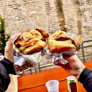 two people holding sandwiches