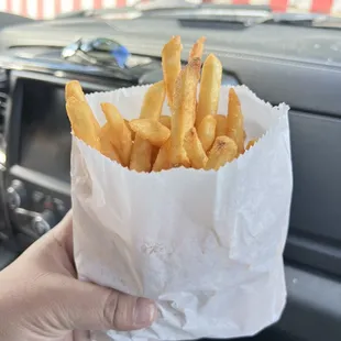 a person holding a bag of french fries