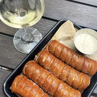 a tray of pretzels and a glass of white wine