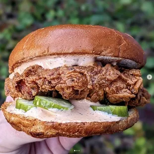 a hand holding a fried chicken sandwich